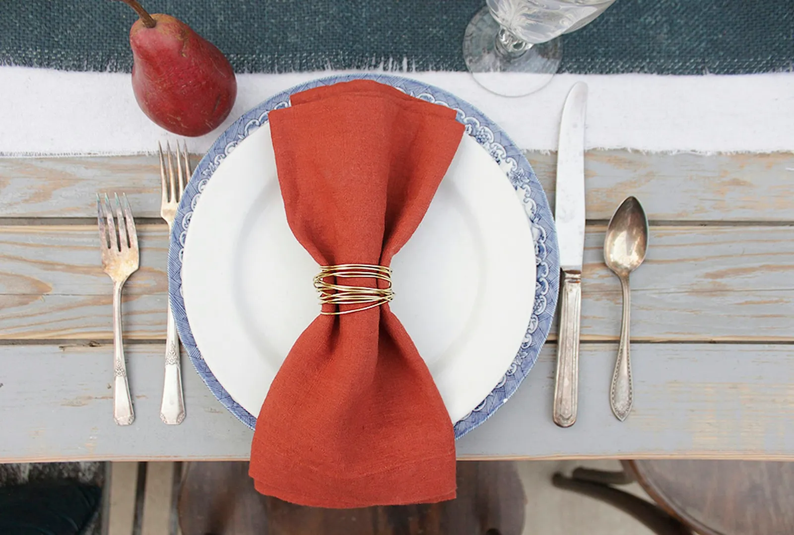 Gold wire napkin rings being used with rust-colored napkins on a fall table.
