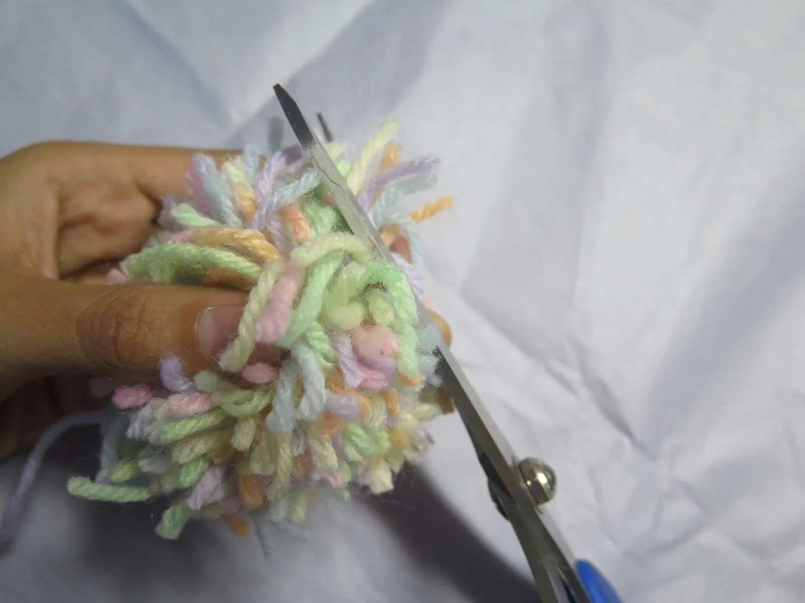Trimming a bundle of yarn to create a pompom shape
