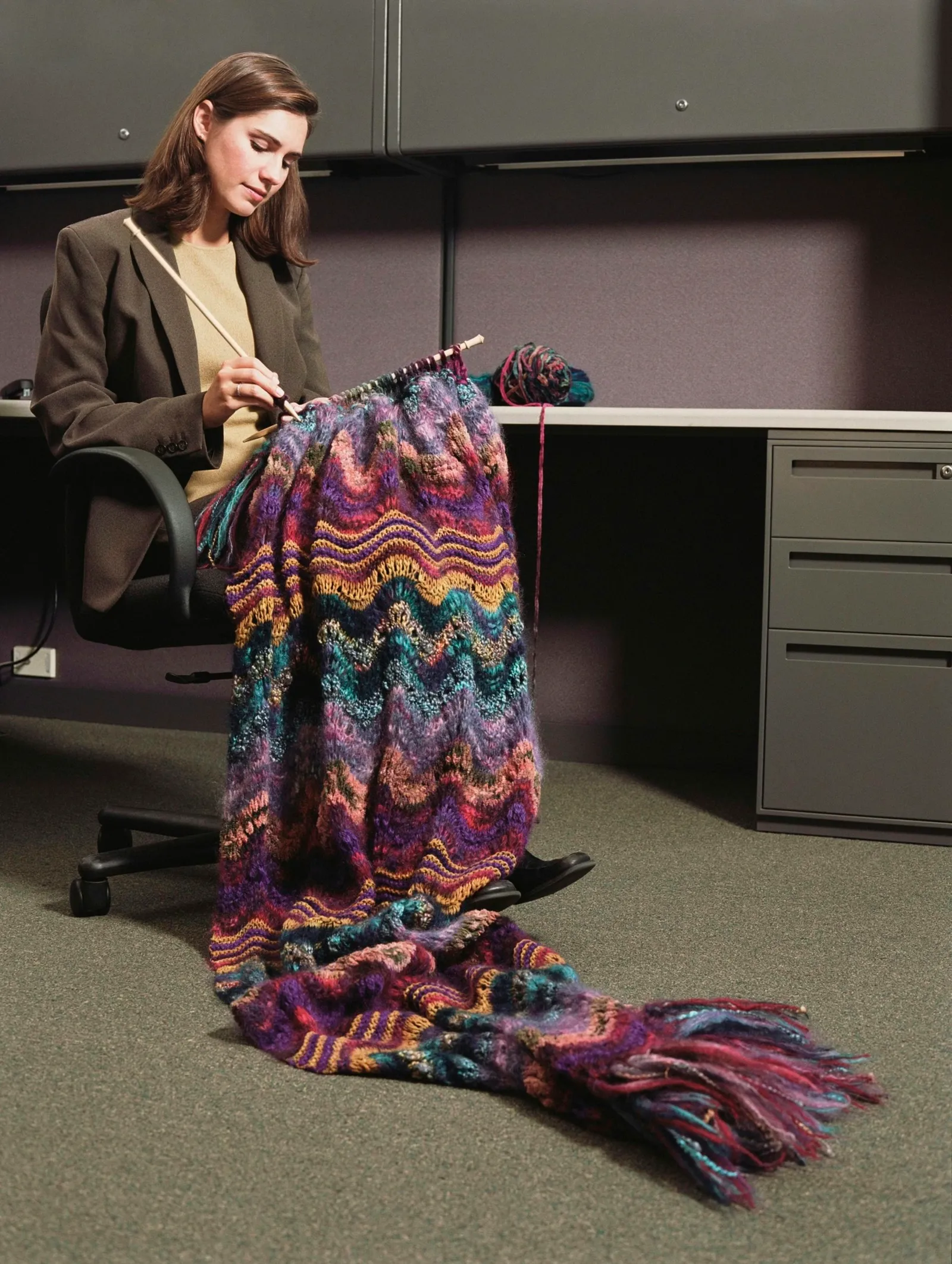 Businesswoman sitting at a desk knitting