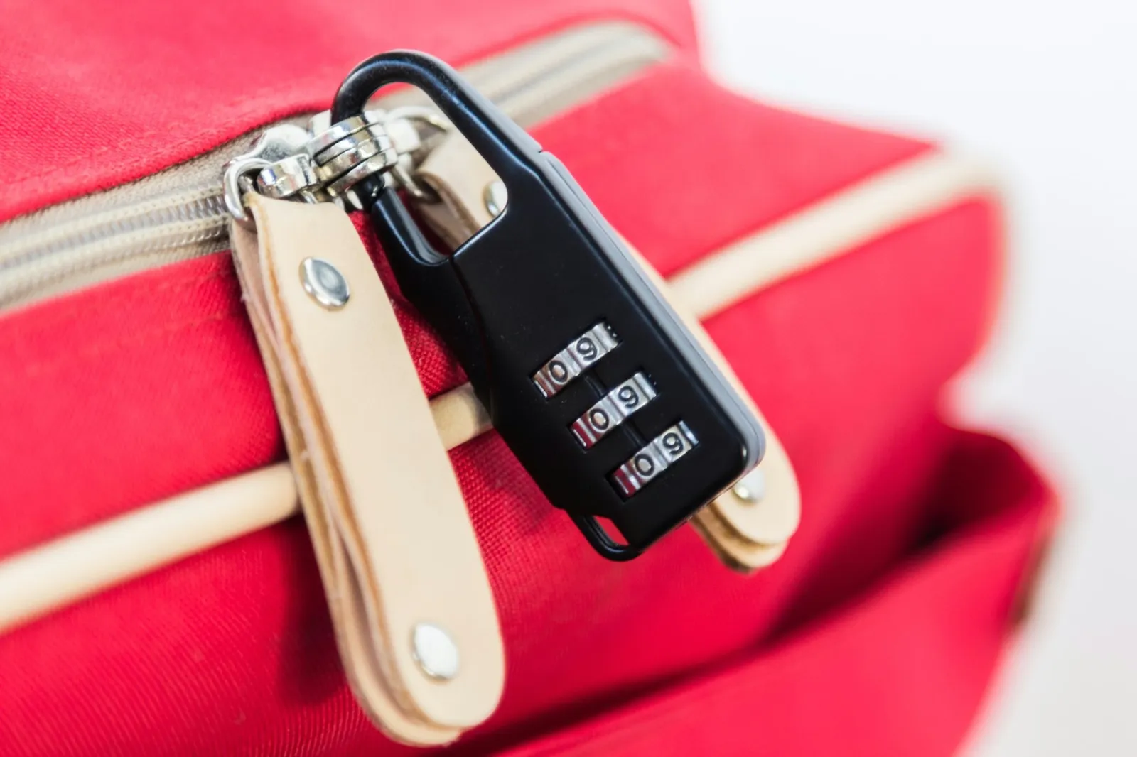 Black 3 digit padlock on red luggage.