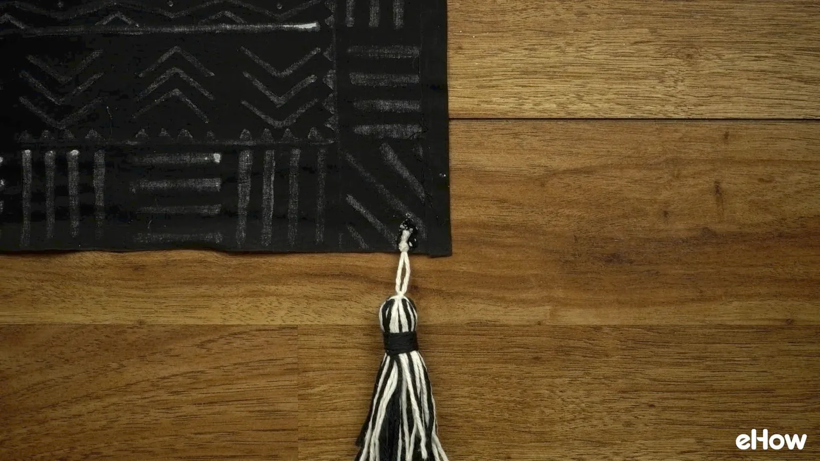 Gluing tassel on DIY mudcloth-inspired wall hanging.