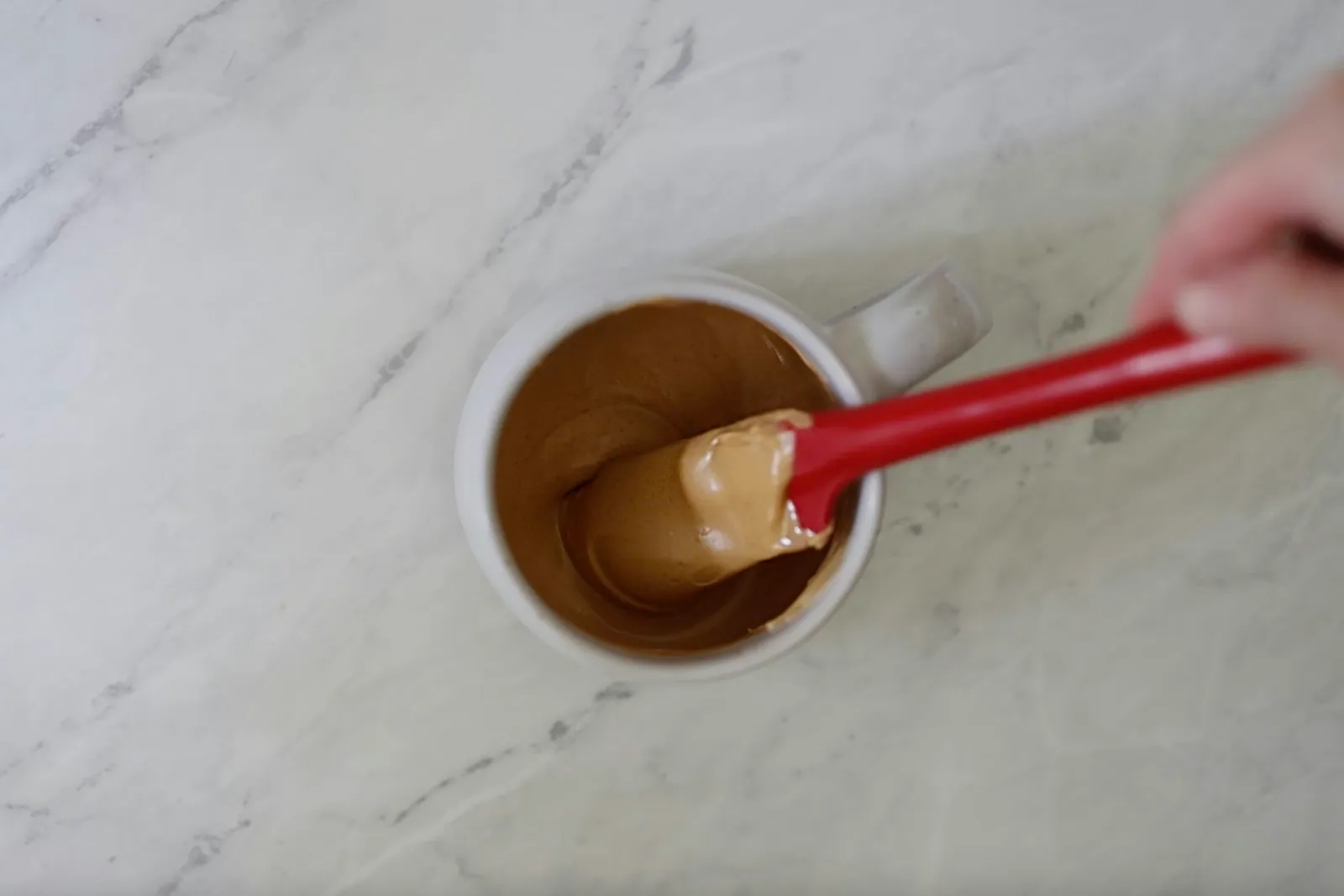 Stirring melted peanut butter candy melts in a mug