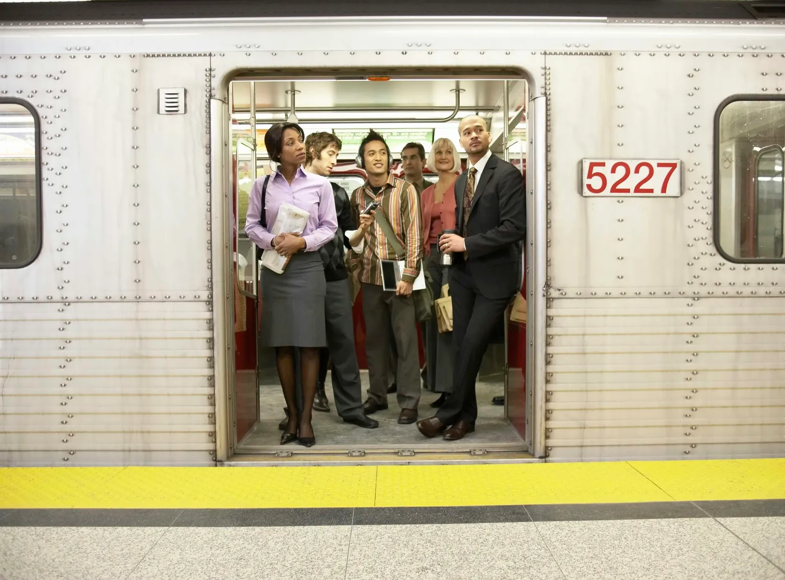 Medium group of people standing in subway train doorway