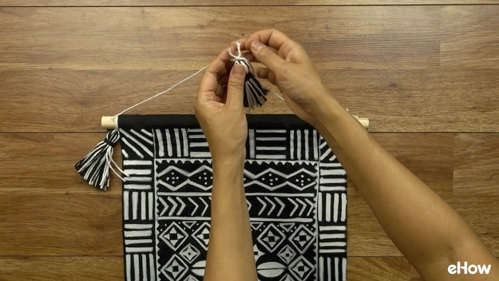 Preparing to hang DIY mudcloth-inspired wall hanging.